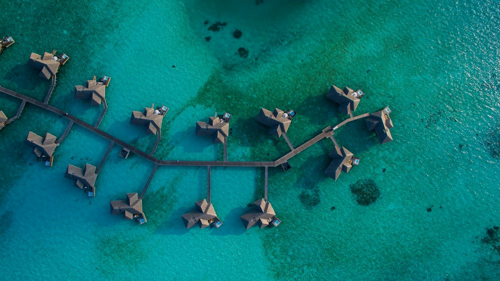 Aerial view of overwater resort villas in a turquoise Maldives lagoon